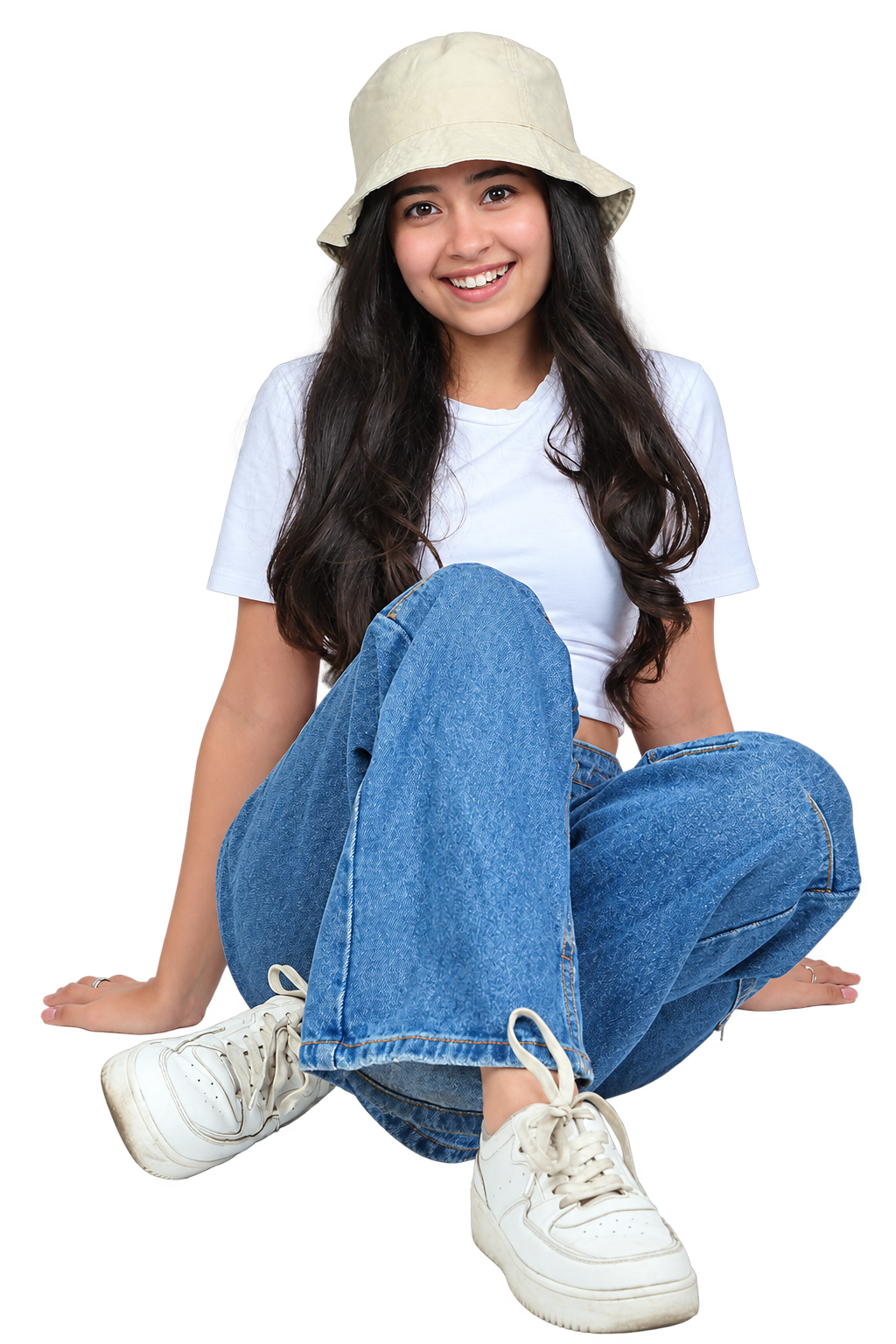 Fotografía ilustrativa: modelo sonriendo en una sesión de estudio, sentada con jean, remera blanca, sombrero y zapatillas.